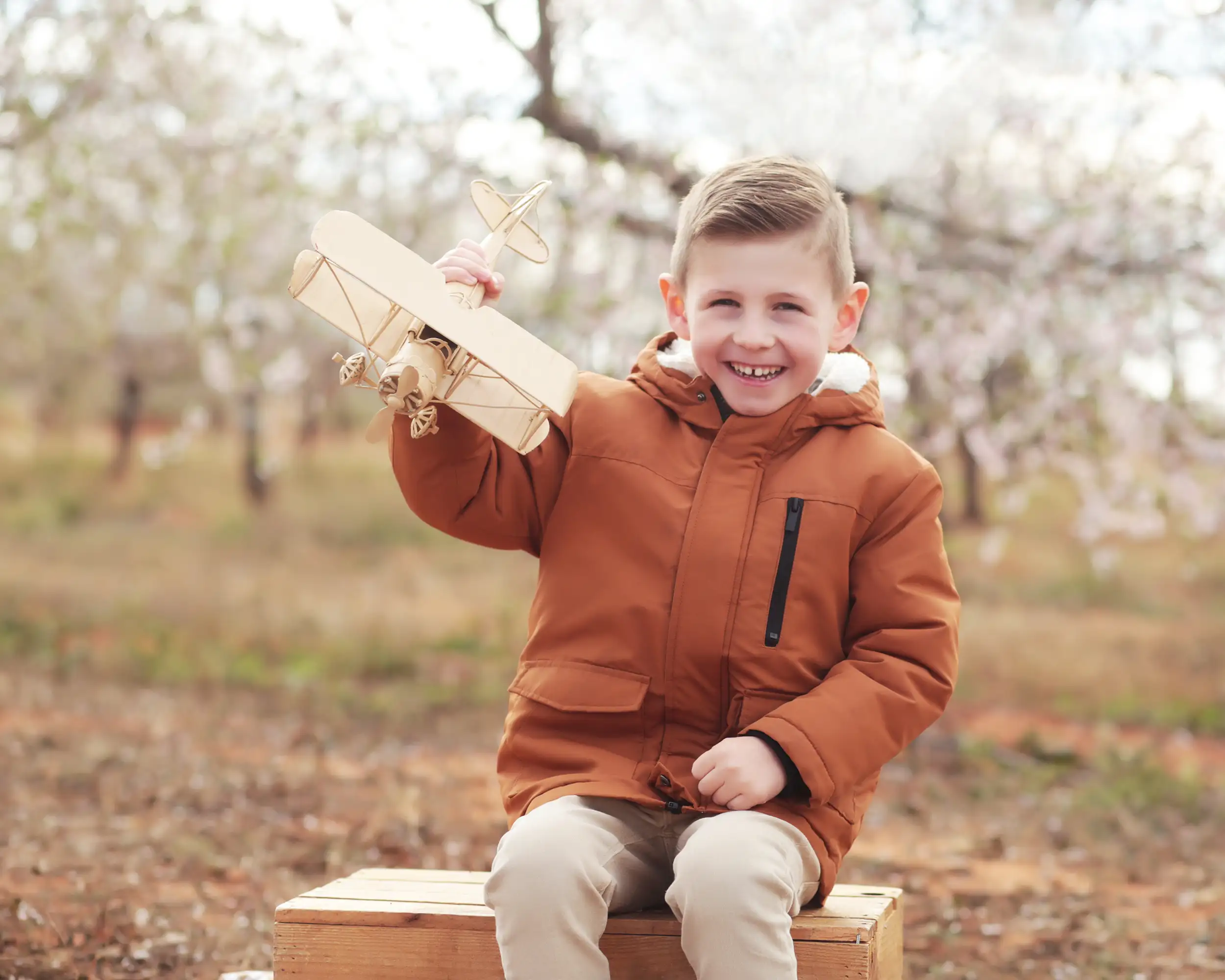 Foto de un niño muy guapo jugando con un avión en el campo